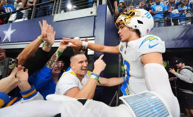 Los Angeles Chargers quarterback Justin Herbert (10) celebrates with fans after a win over the Dallas Cowboys in an NFL football game Sunday, Dec. 21, 2025, in Arlington, Texas. (AP Photo/Julio Cortez)