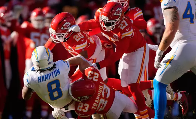 Los Angeles Chargers running back Omarion Hampton (8) is stopped by Kansas City Chiefs' Nohl Williams (20), Chamarri Conner (27) and Drue Tranquill (23) during the first half of an NFL football game Sunday, Dec. 14, 2025, in Kansas City, Mo. (AP Photo/Charlie Riedel)