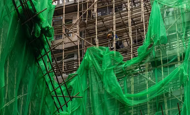 Construction workers remove scaffolding nets from a renovation project in Quarry Bay district after the deadly fire at Wang Fuk Court, in the Tai Po district of Hong Kong's New Territories, Thursday, Dec 4, 2025. (AP Photo/Chan Long Hei)