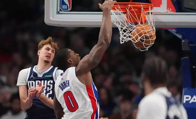 Detroit Pistons center Jalen Duren (0) dunks as Dallas Mavericks' Cooper Flagg (32) defends in the first half of an NBA basketball game in Dallas, Thursday, Dec. 18, 2025. (AP Photo/Tony Gutierrez)