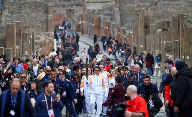 Actor Jackie Chan holds the olympic torch passing through the Archaeological Park in Pompeii, Italy, Monday, Dec. 22, 2025. (Alessandro Garofalo/LaPresse via AP)