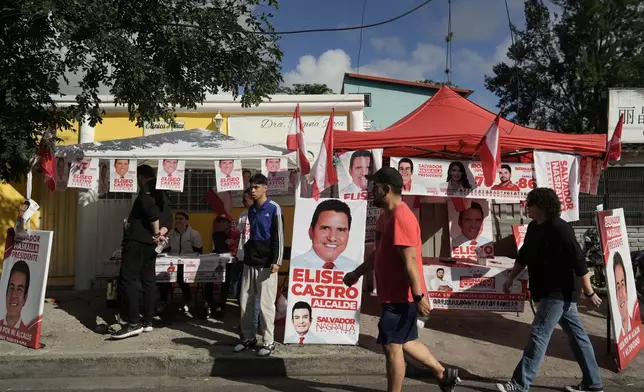 People walk past a candidate's stand with campaign materials during general elections in Tegucigalpa, Honduras, Sunday, Nov. 30, 2025. (AP Photo/Emmanuel Andres)