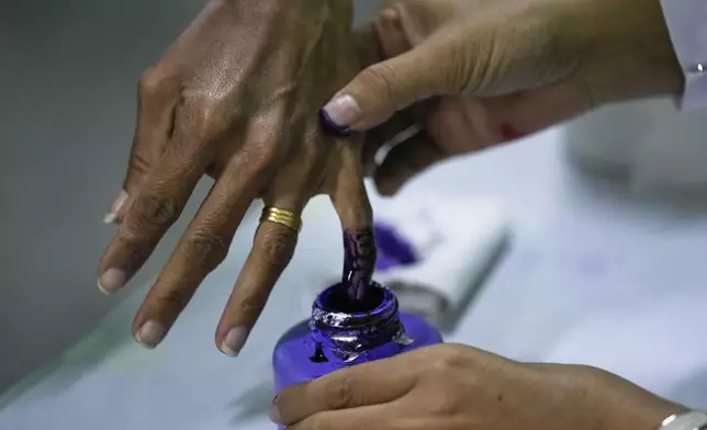 A voter dips their finger in an ink bottle after casting a ballot at a polling station in Naypyitaw, Myanmar, Sunday, Dec. 28, 2025. (AP Photo/Aung Shine Oo)
