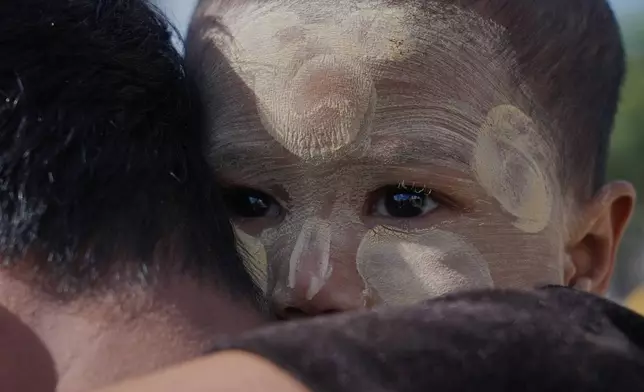 A father carrying his child lines up to cast vote at a polling station in Naypyitaw, Myanmar, Sunday, Dec. 28, 2025. (AP Photo/Aung Shine Oo)