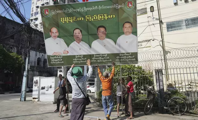 Members of the military-backed Union Solidarity and Development Party (USDP) remove a campaign poster during the last day of the first phase of an election campaign in Yangon, Myanmar, Friday, Dec. 26, 2025. (AP Photo/Thein Zaw)
