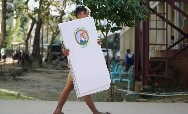 A volunteer of the Union Election Commission carries election materials as they prepare to set up a polling station opened at a school one day ahead of the first phase of the general election in Yangon, Myanmar, Saturday, Dec. 27, 2025. (AP Photo/Thein Zaw)