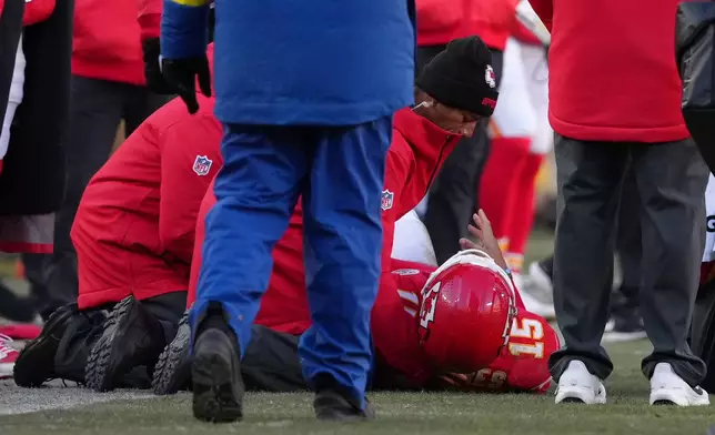 Kansas City Chiefs quarterback Patrick Mahomes (15) is checked on after being injured during the second half of an NFL football game against the Los Angeles Chargers Sunday, Dec. 14, 2025, in Kansas City, Mo. (AP Photo/Ed Zurga)