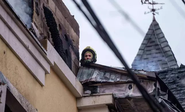 A rescue worker clears the rubble of a house destroyed after a Russian strike on Kyiv, Ukraine, on Saturday, Dec. 27, 2025. (AP Photo/Evgeniy Maloletka)