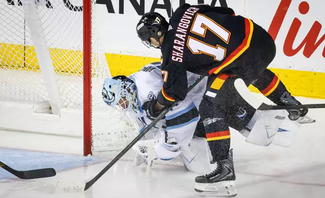 Utah Mammoth goalie Vitek Vanecek, left, collides with Calgary Flames' Yegor Sharangovich during the second period of an NHL hockey game in Calgary, Saturday, Dec. 6, 2025. (Jeff McIntosh/The Canadian Press via AP)
