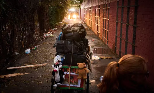 A migrant's belongings are packed before he leaves as police in the background prepares to carry out eviction orders at an abandoned school building where hundreds of mostly undocumented migrants had been living, in Badalona, near Barcelona, Spain, Wednesday, Dec. 17, 2025. (AP Photo/Emilio Morenatti)