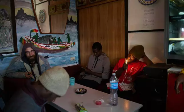 Migrants from Romania and Senegal sit in a makeshift bar inside an abandoned school in Badalona, near Barcelona, Spain, Monday, Dec. 15, 2025, where hundreds of migrants have been occupying the building. (AP Photo/Emilio Morenatti)