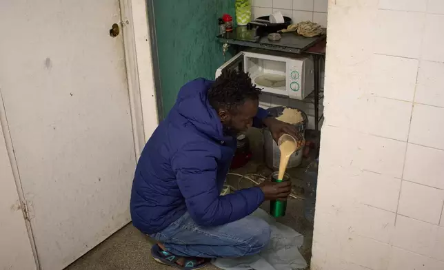 Yankuba Touray, from Gambia, makes coffee in a makeshift kitchen inside an abandoned school in Badalona, near Barcelona, Spain, Tuesday, Dec. 16, 2025, where hundreds of migrants have been occupying the building. (AP Photo/Emilio Morenatti)