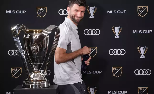 Vancouver Whitecaps' Thomas Muller looks at the MLS Cup trophy as he arrives for a news conference Thursday, Dec. 4, 2025, in Fort Lauderdale, Fla., ahead of Saturday's of the MLS Cup soccer match against Inter Miami. (Darryl Dyck/The Canadian Press via