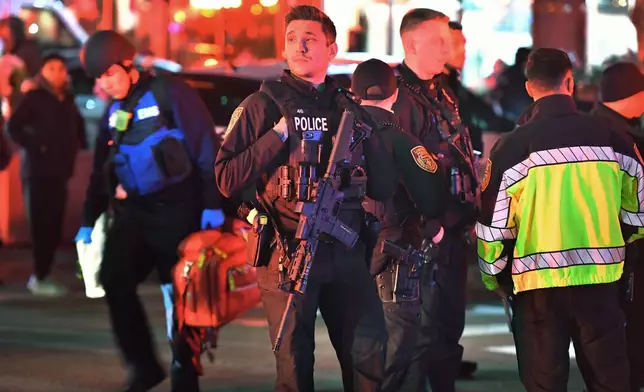 Law enforcement officials carrying weapons gather near Brown University in Providence, R.I., on Saturday, Dec. 13, 2025, during the investigation of a shooting. (AP Photo/Steven Senne)
