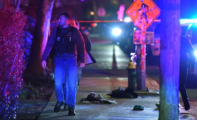 A law enforcement official walks past articles of clothing on a sidewalk near an entrance to Brown University, Saturday, Dec. 13, 2025, in Providence, R.I., during the investigation of a shooting. (AP Photo/Steven Senne)