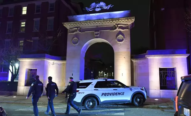 Law enforcement officials walk near an entrance to Brown University in Providence, R.I., on Saturday, Dec. 13, 2025, during the investigation of a shooting. (AP Photo/Steven Senne)