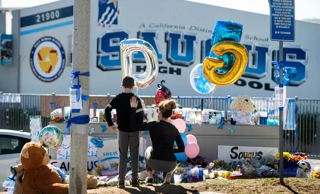 FILE - Michelle Bosshard and her son Lucas visit a memorial on Nov. 18, 2019, for two students killed during a shooting at Saugus High School in Santa Clarita, Calif., days before. (Sarah Reingewirtz/The Orange County Register via AP, File)