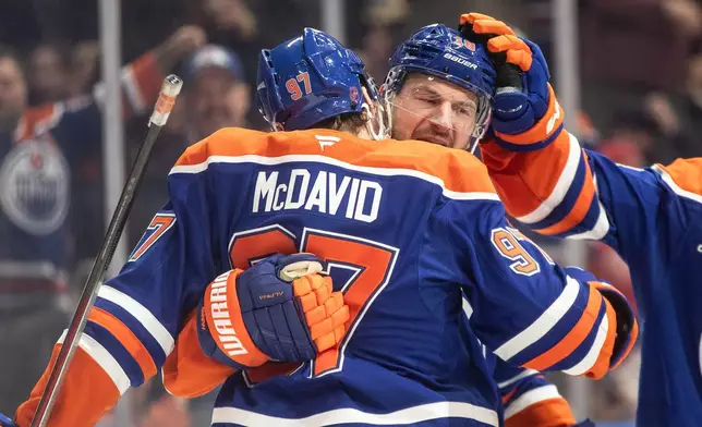 Edmonton Oilers' Connor McDavid (97) and Zach Hyman (18) celebrate a goal against the Detroit Red Wings during second period NHL action, in Edmonton on Thursday, Dec. 11, 2025. (Jason Franson/The Canadian Press via AP)