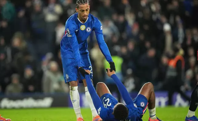 Chelsea's Joao Pedro, top, helps Wesley Fofana stand up after the English Premier League soccer match between Chelsea and Bournemouth in London, England, Tuesday, Dec. 30, 2025. (AP Photo/Kin Cheung)