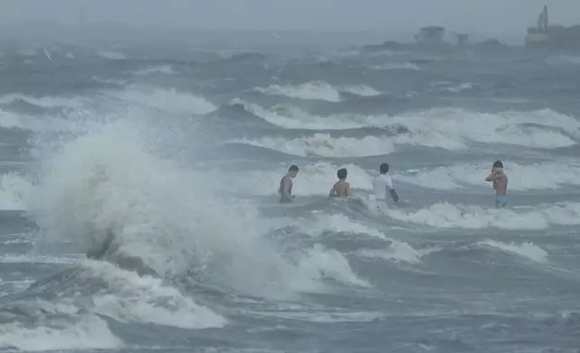 FILE - Men swim despite strong waves due to Typhoon Fung-wong along a coastal village on Nov. 10, 2025, in Navotas, Philippines. (AP Photo/Aaron Favila, File)