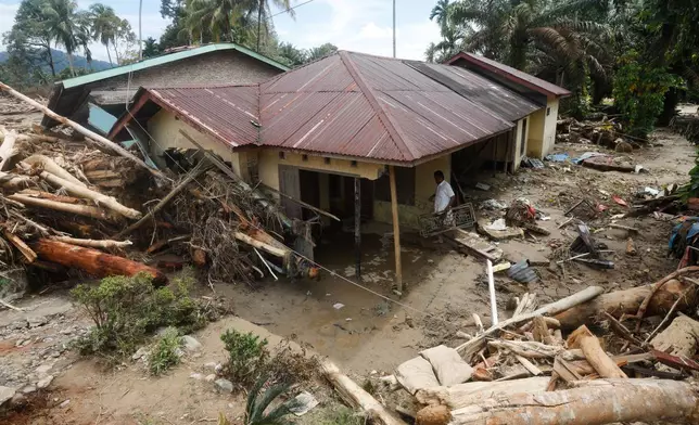 A man cleans his house at a village affected by flood in Batang Toru, North Sumatra, Indonesia, Wednesday, Dec. 3, 2025. (AP Photo/Binsar Bakkara)