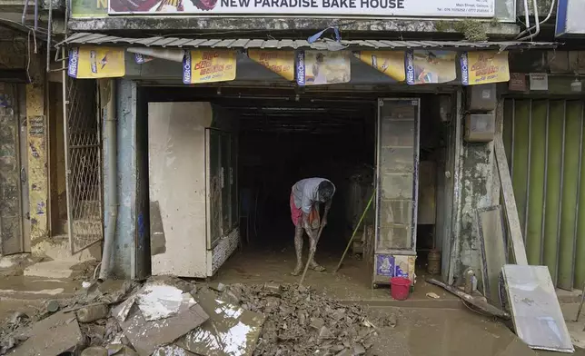 A man cleans the mud and slush from his shop after floods in Gelioya, Sri Lanka Sri Lanka, Monday, Dec. 1, 2025. (AP Photo/Eranga Jayawardena)