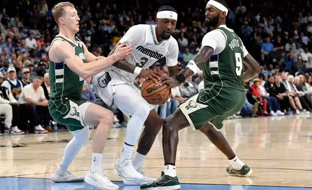 Memphis Grizzlies guard Kentavious Caldwell-Pope (3) handles the ball between Milwaukee Bucks guard AJ Green, left, and forward Bobby Portis (9) in the first half of an NBA basketball game, Friday, Dec. 26, 2025, in Memphis, Tenn. (AP Photo/Brandon Dill)