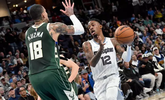 Memphis Grizzlies guard Ja Morant (12) drives against Milwaukee Bucks forward Kyle Kuzma (18) in the first half of an NBA basketball game Friday, Dec. 26, 2025, in Memphis, Tenn. (AP Photo/Brandon Dill)