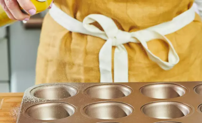 A woman applies non-stick spray to a muffin tin in New York on Oct. 23, 2023. (Cheyenne M. Cohen via AP)