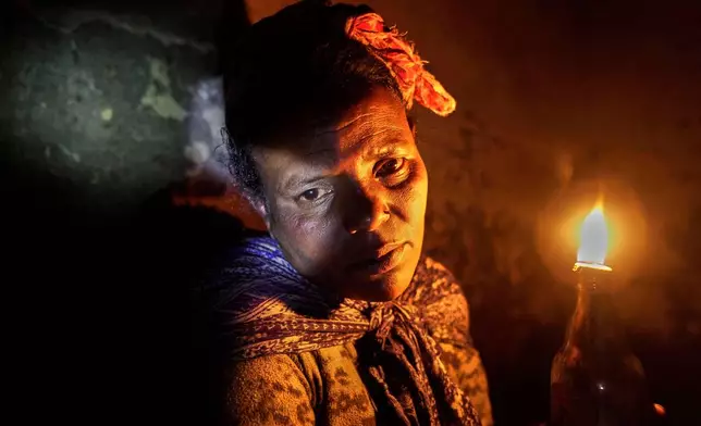 Fanuse Adete, 38, holds up a candle she uses to light her home at night in the Menabichu district on the outskirts of Addis Ababa, Ethiopia, Sept. 6, 2025. (AP Photo/Brian Inganga, File)