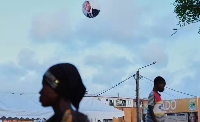 A balloon bearing the image of President Alassane Ouattara floats above supporters during a campaign rally in Koumassi, Abidjan, Ivory Coast, Oct. 22, 2025. (AP Photo/Misper Apawu, File)