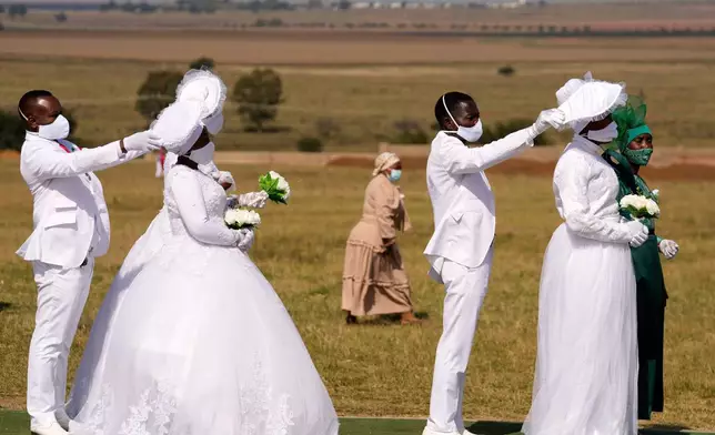 Groomsmen shield their brides from the sun as they queue for an Easter mass wedding at The International Pentecost Holiness Church in Heidelberg, South Africa, April 20, 2025. (AP Photo/Themba Hadebe, File)