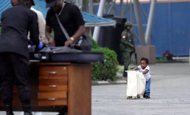 A child pushes a suitcase towards Rwanda security officials checking people crossing from Congo in Gisenyi, Rwanda, Jan. 29, 2025, following M23 rebels' advances into eastern Congo's capital Goma. (AP Photo/Brian Inganga)
