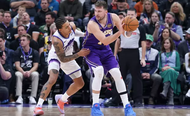 Los Angeles Lakers guard Luka Doncic (77) posts up against Utah Jazz guard Keyonte George, left, during the second half of an NBA basketball game, Thursday, Dec. 18, 2025, in Salt Lake City. (AP Photo/Rob Gray)