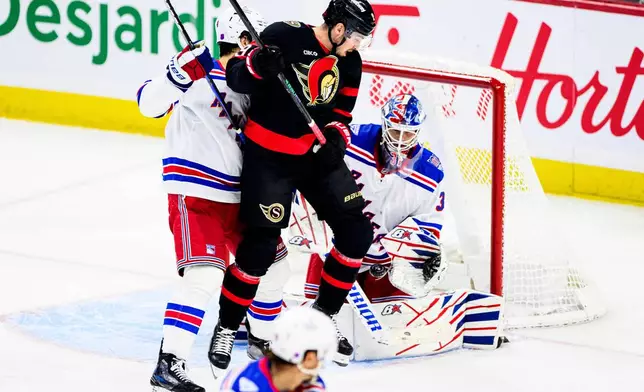 New York Rangers goaltender Igor Shesterkin (31) tracks the puck through teammate Braden Schneider (left) and Ottawa Senators' Drake Batherson (19) during third period NHL hockey action in Ottawa, on Thursday, Dec. 4, 2025.(Spencer Colby/The Canadian Press via AP)