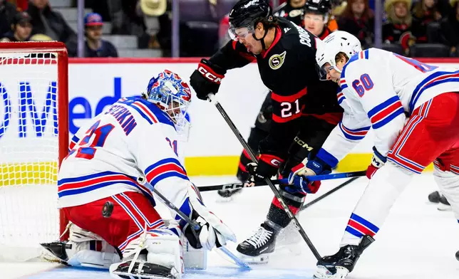 New York Rangers goaltender Igor Shesterkin, left, makes a save against Ottawa Senators' Nick Cousins (21) as Rangers' Scott Morrow (60) defends during second-period NHL hockey game action in Ottawa, Ontario, Thursday, Dec. 4, 2025. (Spencer Colby/The Canadian Press via AP)