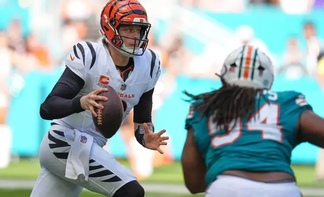 Cincinnati Bengals quarterback Joe Burrow, left, scrambles during the first half of an NFL football game against the Miami Dolphins, Sunday, Dec. 21, 2025, in Miami Gardens, Fla. (AP Photo/Rebecca Blackwell)