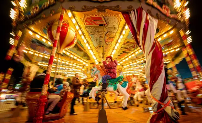 FILE - A child rides on a merry-go-round at a Christmas fair in Bucharest, Romania, Dec. 3, 2025. (AP Photo/Andreea Alexandru, File)