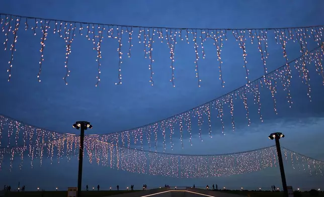 FILE - People walk along Kabatas ferry terminal decorated with lights for the holidays, in Istanbul, Turkey, Dec. 10, 2025. (AP Photo/Francisco Seco, File)
