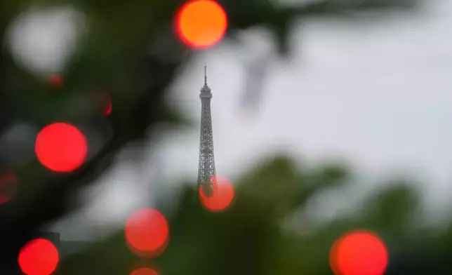 FILE - The Eiffel Tower is framed by Christmas tree decorations that adorn the Les Galeries Lafayette department store rooftop in Paris, Dec. 1, 2025. (AP Photo/Aurelien Morissard, File)