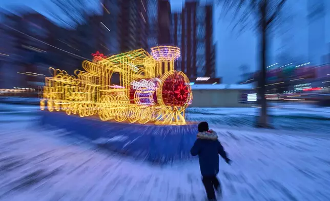 FILE - A boy runs toward a model train illuminated with holiday lights in St. Petersburg, Russia, Dec. 15, 2025. (AP Photo/Dmitri Lovetsky, File)