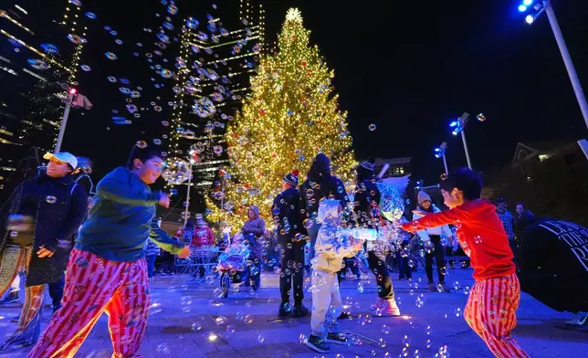 FILE - Gabriel Taylor, center, sprays other children with bubbles at Sundance Square after a Christmas tree lighting ceremony, in Fort Worth, Texas, Dec. 2, 2025. (AP Photo/Tony Gutierrez, File)