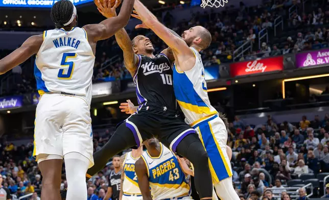 Sacramento Kings guard Demar Derozan (10) shoots while being defend by Indiana Pacers center Jay Huff, right, and forward Jarace Walker (5) during the first half of an NBA basketball game in Indianapolis, Monday, Dec. 8, 2025. (AP Photo/Doug McSchooler)