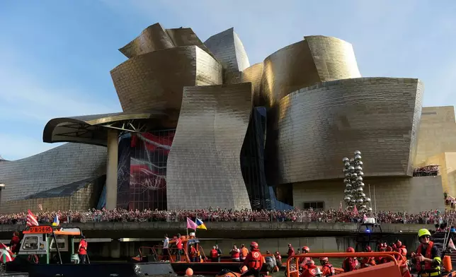 FILE - Athletic Bilbao fans wait in front of the Guggenheim museum as support boats pass before team celebrations on the Nervion Estuary in Bilbao, Spain, Thursday, April 11, 2024. (AP Photo/Alvaro Barrientos, File)