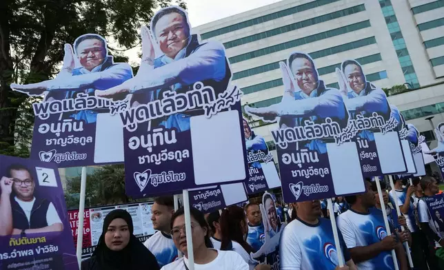 Supporters of Thailand's Prime Minister and leader of Bhumjaithai Party Anutin Charnvirakul, hold poster during a candidate registration in Bangkok, Thailand, Sunday, Dec. 28, 2025. (AP Photo/Sakchai Lalit)
