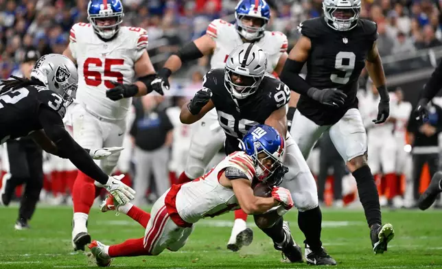 Las Vegas Raiders defensive tackle Thomas Booker IV (99) tackles New York Giants wide receiver Wan'Dale Robinson (17) during the first half of an NFL football game Sunday, Dec. 28, 2025, in Las Vegas. (AP Photo/David Becker)