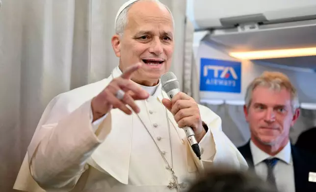 Pope Leo XIV talks to reporters aboard an airplane as he returns from a six-day visit to Turkey and Lebanon, Tuesday, Dec. 2, 2025. (Alessandro Di Meo/Pool Photo via AP)