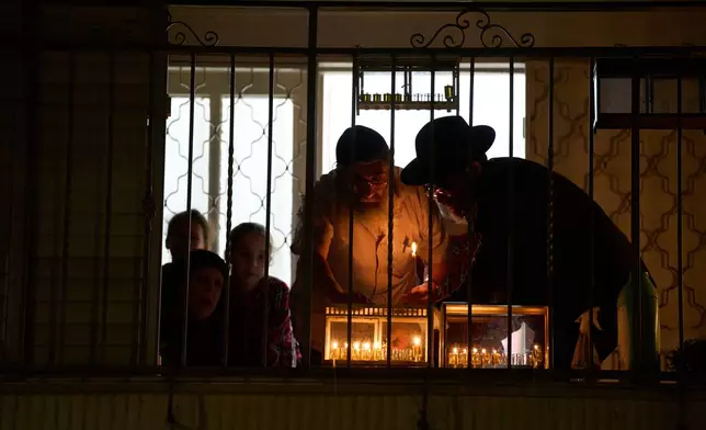 Ultra-Orthodox Jewish family light candles in the fifth night of Hanukkah in Haifa, Israel, Thursday, Dec. 18, 2025. (AP Photo/Ariel Schalit)