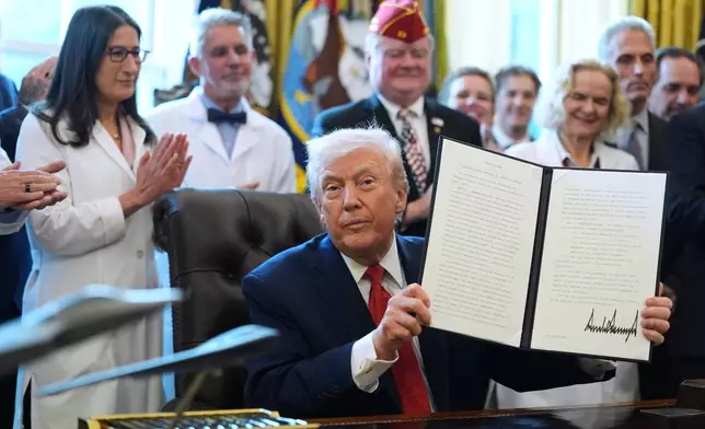 President Donald Trump displays an executive order reclassifying marijuana as a less dangerous drug in the Oval Office of the White House, Thursday, Dec. 18, 2025, in Washington. (AP Photo/Evan Vucci)