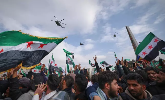 Army helicopters fly overhead during a parade by the new Syrian army marking the first anniversary of the ousting of the Bashar Assad regime in Damascus, Syria, Monday, Dec. 8, 2025. (AP Photo/Ghaith Alsayed)